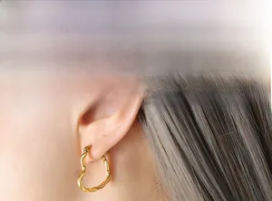 Gros plan d'une boucle d'oreille créole cœur torsadée dorée portée par un mannequin en détail