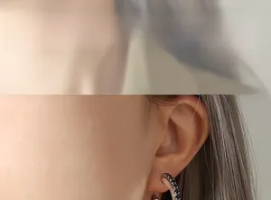 Gros plan de boucles d'oreilles en C argentées serties de zircons noirs sur mannequin