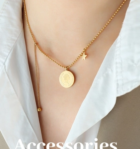 Détail d'un collier avec pendentif pièce dorée et breloque étoile sur chaîne perlée
