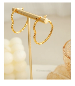 Détail de boucles d'oreilles cœur dorées texturées sur un présentoir en métal luxueux