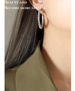 Détail de créoles en argent avec pavé de zircons blancs sur l'oreille du mannequin