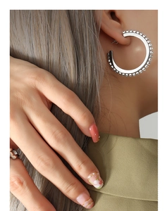 Gros plan d'une boucle d'oreille créole en C argentée sertie de zircons sur un mannequin