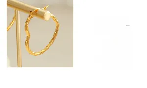 Détail de boucles d'oreilles cœur dorées avec texture de corde torsadée et contour irrégulier