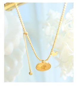 Gros plan d'un collier à billes dorées avec pendentif pièce portrait et étoile