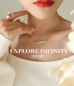Collier en perles d'eau douce naturelles et bague dorée portés par une femme en tricot