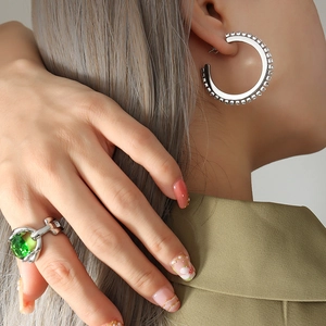 Boucles d'oreilles créoles strass argent et bague grosse pierre verte sur modèle