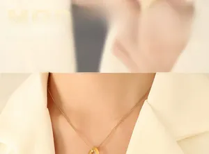 Détail du collier avec pendentif géométrique doré torsadé porté par un mannequin
