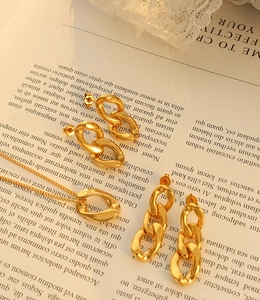 Ensemble artistique de boucles d'oreilles et collier à maillons dorés sur fond de magazine