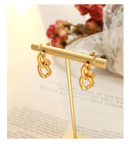 Détail des boucles d'oreilles à maillons torsadés dorés sur un décor vintage de style français