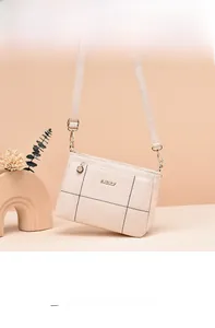Detail shot of a cream quilted crossbody bag with gold metal logo and adjustable strap