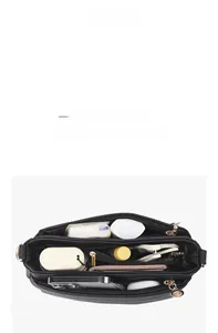 Top view of spacious interior of black pebble leather crossbody bag with items inside