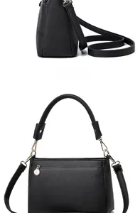 Detail of black litchi texture leather handbag with gold hardware and logo pendant