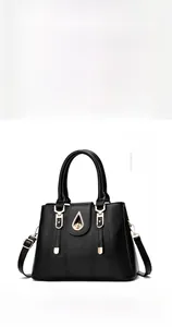 Close-up of litchi texture leather and golden metal twist lock on black handbag