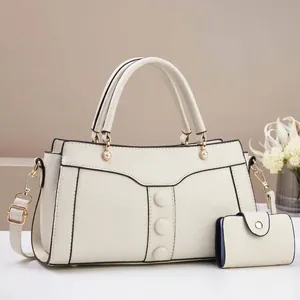 Detail of off-white lychee leather handbag with pearl accents and contrast edge