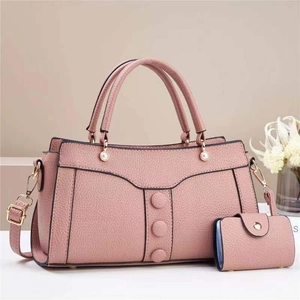 Detail of pink lychee leather handbag with decorative buttons and pearl hardware