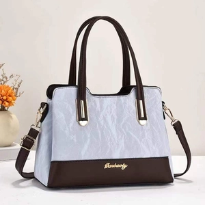Dettaglio della borsa con trama marmo blu e base in pelle marrone in primo piano