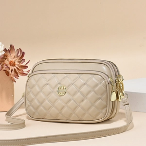 Beige quilted leather crossbody bag featuring three zipper pockets and gold hardware