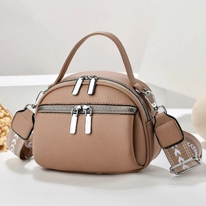 Detail of light brown lychee leather crossbody bag with dual silver zippers and patterned strap