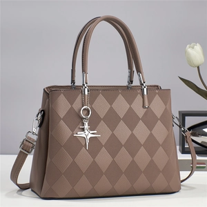 Macro detail of brown quilted crossbody bag with star pendant and textured leather finish