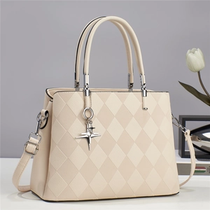 Detail of quilted leather texture and silver cross star pendant on cream tote bag