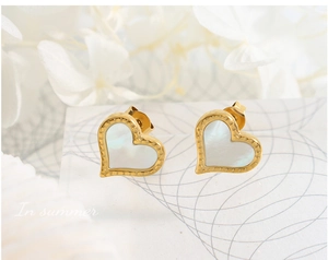 Détail de boucles d'oreilles cœur en plaqué or 18K avec nacre blanche naturelle