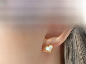 Détail d'une boucle d'oreille en nacre en forme de cœur avec bordure perlée dorée