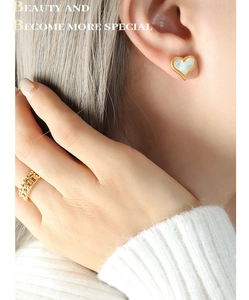 Vue macro des boucles d'oreilles cœur dorées avec nacre et d'une bague maille gourmette