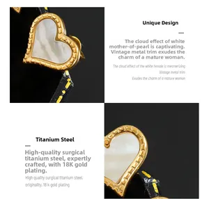 Détail des boucles d'oreilles cœur en nacre blanche avec une finition en acier plaqué or 18K