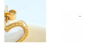 Gros plan de boucles d'oreilles cœur en plaqué or 18K avec incrustation de nacre
