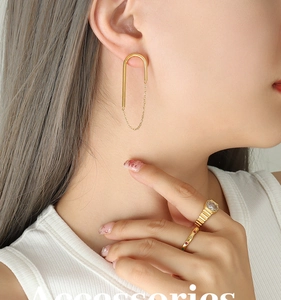 Détail de boucles d'oreilles U à chaîne dorée 18 carats et bagues assorties sur mannequin
