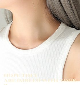 Gros plan de boucles d'oreilles chaîne dorées à l'or 18k portées avec un style minimaliste