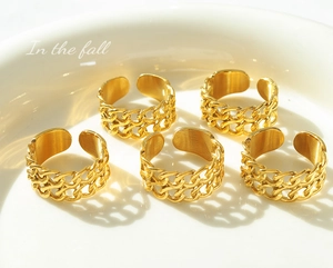 Detailed view of five adjustable 18k gold plated chain link rings on a ceramic tray