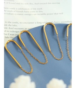 Vue macro de quatre boucles d'oreilles dorées en U sur une assiette en céramique bleue