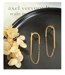 Détail de boucles d'oreilles chaîne en U plaqué or 18k sur céramique noire mate