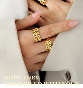 Detail of layered gold double chain rings worn by a model with a minimalist aesthetic