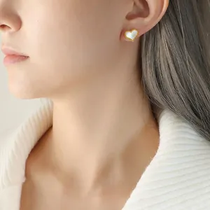 Boucles d'oreilles cœur vintage en or 18K avec nacre blanche portées par un mannequin