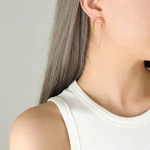 Boucle d'oreille chaîne en forme de U plaquée or 18k portée par un mannequin sur fond gris