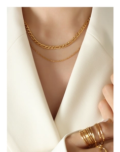 Détail de colliers superposés dorés et de bagues empilables au style minimaliste