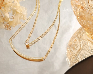 Close-up of double-layer gold necklace with sparkling zircon studs and curved pendant