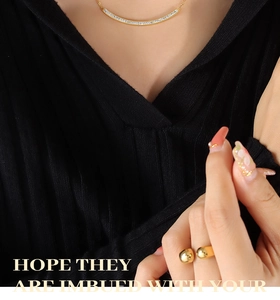 Macro detail of gold-plated smile necklace with pavé zircons and sphere open ring