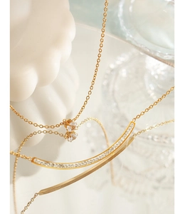 Macro shot of double-layered gold necklace with zircon bar and solitaire crystal pendant