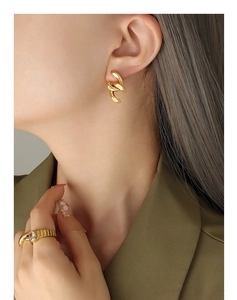 Gros plan de boucles d'oreilles gourmettes en or 18 carats et d'une bague à pierre ovale