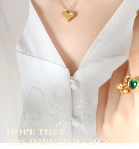 Vue macro d'un collier cœur en or 18k avec zircon et bague émeraude chic