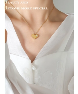 Gros plan d'un collier pendentif cœur doré avec zircon porté sur une chemise blanche chic