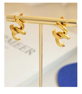 Détail de boucles d'oreilles entrelacées plaquées or 18 carats sur un support