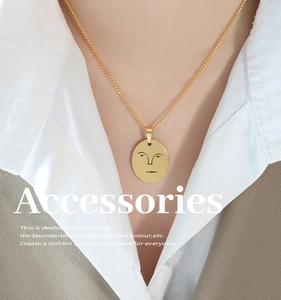 Gros plan d'un collier à pendentif ovale doré avec motif de visage minimaliste