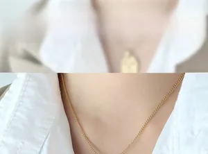 Gros plan d'un collier chaîne torsadée dorée minimaliste porté par un mannequin en chemise