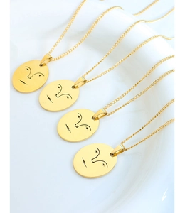 Détail de quatre colliers dorés avec pendentifs ovales au design de traits de visage épurés