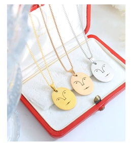 Gros plan de pendentifs visages abstraits minimalistes en or, or rose et argent poli