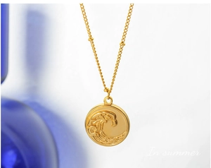 Détail du collier plaqué or 18 carats avec relief de vagues sur le pendentif rond
